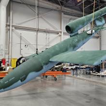 A missile with fresh new paint hangs diagonally from the ceiling in a hangar.