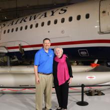 Two people stand in front of an aircraft. 