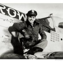 Bud Anderson, a white man, sits on the wing of an airplane.