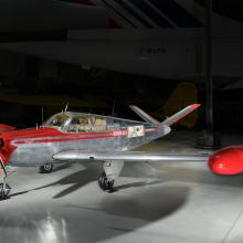 Silver and red painted single engine aircraft with four seats.