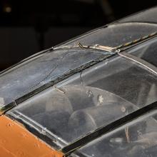 Top view of cockpit of an airplane. The airplane is painted orange and the cockpit window is closed. 