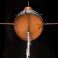 Front view of nose of an aircraft. The aircraft is painted orange. 