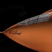 Side view of nose of an aircraft. The aircraft is painted orange. 