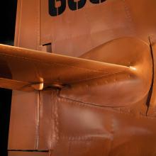 Close up of vertical and horizontal stabilizer of an aircraft. The aircraft is painted orange. 