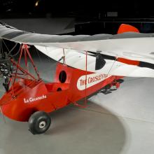 Wing of a red and white open-cockpit staggered wing aircraft 