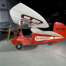 Wing and propellers of a red and white open-cockpit staggered wing aircraft 