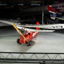 Red and white open-cockpit staggered wing aircraft on display at the museum. 