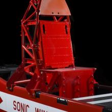 Straight metal seat attached to the middle of a rocket sled. Sonic Wild No 1 is painted on the vehicle. 