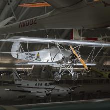 Silver painted biplane with wood propellers. Huff-Daland Duster is painted on the side of the plane.