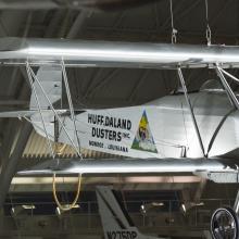 Silver painted fuselage of a biplane. Huff-Daland Duster is painted on the side of the plane.