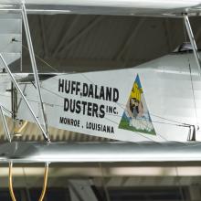 Silver painted fuselage of a biplane. Huff-Daland Duster is painted on the side of the plane.