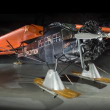 Black and orange painted plane with landing skis. 		