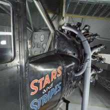 View of the cockpit and engine of an airplane. The words Stars and Stripes are painted on the side of the airplane.