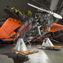 Black and orange painted plane with landing skis. 		