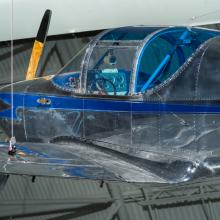 Cockpit and propellers of a aircraft. The cockpit has windows that are blue tinted. 