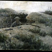 Man in military uniform looks out from a trench. 