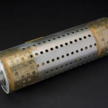 Metal cylindrical tube with small circular holes and tape on edges