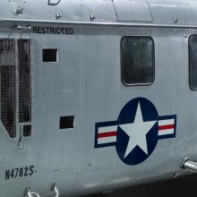 United States Coast Guard insignia painted on the fuselage of a silver helicopter.