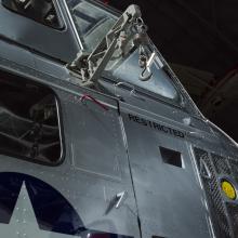 View of a cargo hook, windows, and the word restricted painted on the helicopter. 