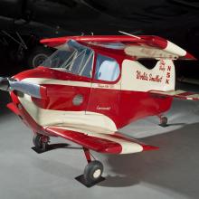 Side view of a red and white painted smallest man-carrying plane.