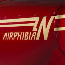 Logo of a plane called Airphibian. The plane is painted red and the logo is painted tan.