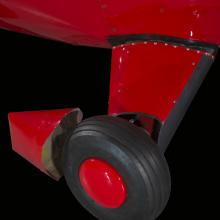 Close up of a tire and landing gear of a red painted plane.