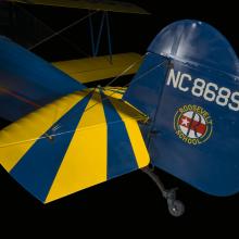 Rudder attached to a yellow and blue painted aircraft. NC8689 is painted on the rudder. 