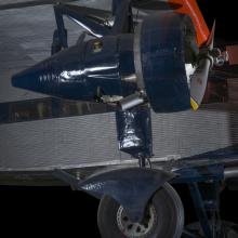 Blue painted engine of an airplane. In the background of the image is an aircraft. 