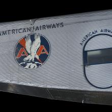 Silver painted fuselage of an airplane. Painted on to the fuselage is an American Airways logo.