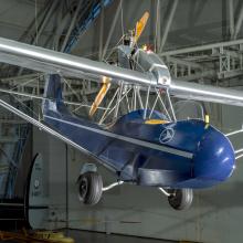 2-place parasol-wing silver and blue monoplane with 45hp Szekely SR-3 Cylinder Model O pusher engine.