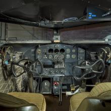 View of the interior cockpit of a plane. In this image are the Instrument panel, seats, and windows of a cockpit of a plane. 