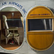 View of the exit door and cabin of a plane. In the plane there is a passenger seat. 