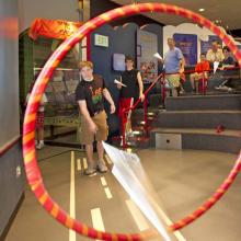 A young man throws a paper plane through a hoop. 