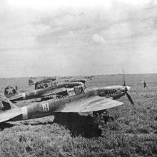 Historical photo of several aircraft on a grassy field. 