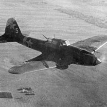 Airplane flies over what appears to be farmland. 