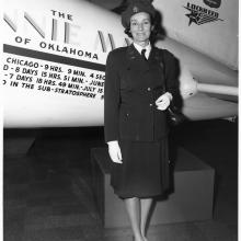 A woman in uniform stands at the side of an aircraft.