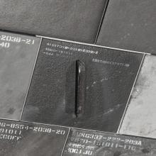 A close-up of several dark tiles with embossed alphanumeric codes and a single metallic handle, suggesting a system of organization or identification, possibly for inventory or categorization purposes.