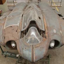 Top view of a gray, World War II era aircraft. On the left side, fairings (material covering gaps on an aircraft) on the aircraft are more rusted in comparison to the right side.