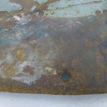 A cover section of a World War II aircraft shows a black surface underneath paint, dirt, grime, and preservatives.