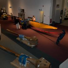 Museum staff members move parts of a large wind tunnel fan around other objects inside the Museum.