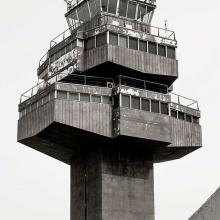 Partial view of the air traffic control tower at Barcelona El-Prat Airport. The tower features a steel base with three floors of operations, each floor smaller than the one before it.