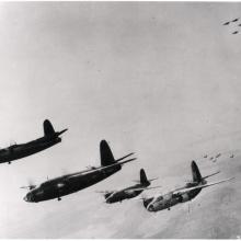 A group of four bomber aircraft fly in the sky during a mission during World War II.