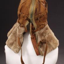 Back view of aviation helmet with leather faceguard and cap and brown fur collar protecting the neck. A full-length zipper and adjustment straps allow for a proper fit. Styled on mannequin.