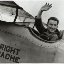 Lt. Apollo Soucek, a white male pilot, waves from the cockpit of an aircraft.