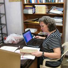 A white, female Museum archivist examines documents owned by author Arthur C. Clarke inside his home.