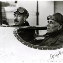 Artur de Sacadura Cabral (on the left) and Gago Coutinho (on the right), both of whom are Portuguese male naval aviators, inside the cockpit of an aircraft.