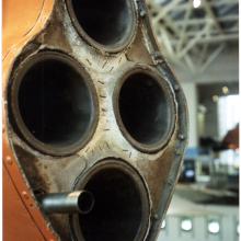 Front of four-rocket engine of orange military monoplane.