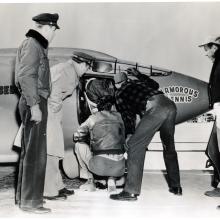 Chuck Yeager, a pilot, prepares for a flight in the cockpit of the Bell X-1 monoplane. Multiple people assist him prior to takeoff.