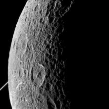 Partial view of a moon belonging to Saturn. The edge is lit by the Sun whereas the rest is facing away from the Sun.