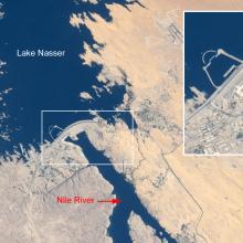 Satellite view of a lake, dam, and surrounding deserts in Egypt. A panel gives a closer perspective of the structure of the dam.